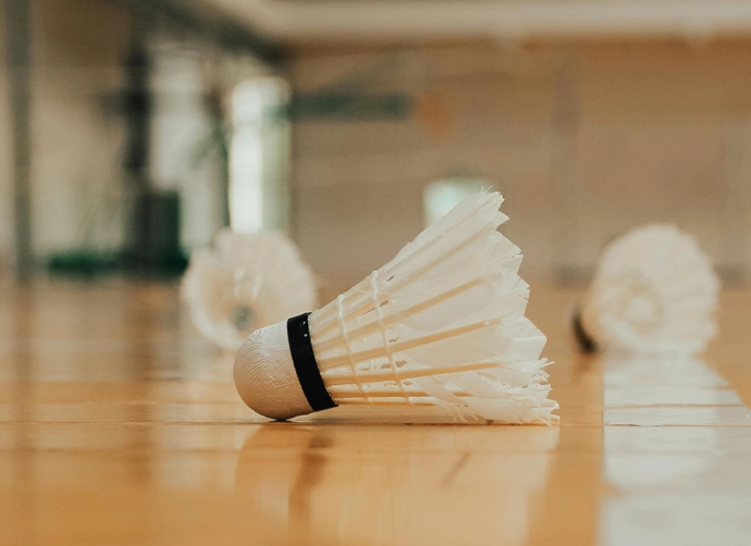 Badmintonbollar på golvet i en idrottshall.
