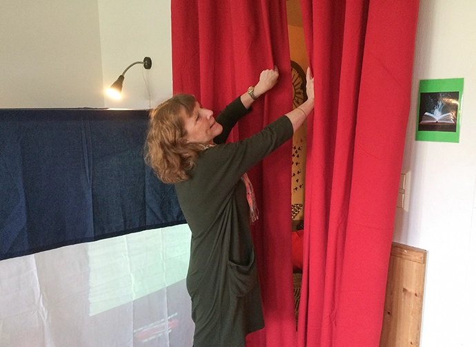 pedagog står och fixar med röd draperier