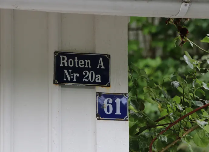 Närbild på en vit träfasad med blå skyltar.