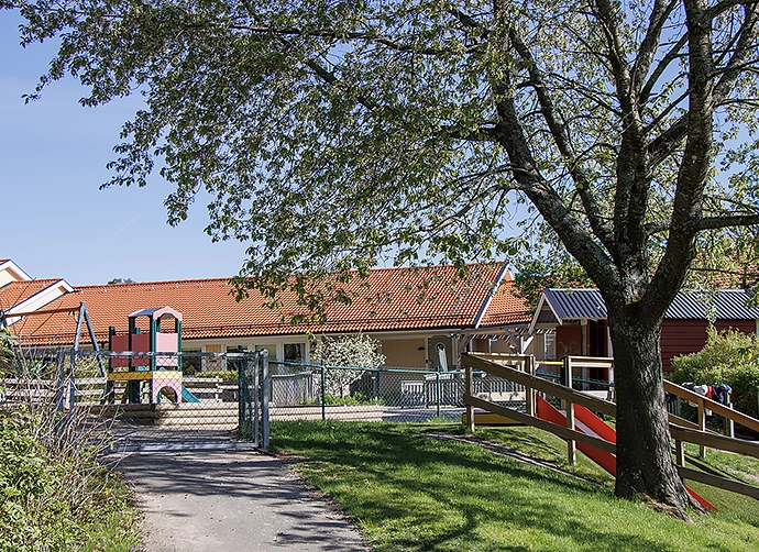 Gång fram till grind till gård och förskola i bakgrunden