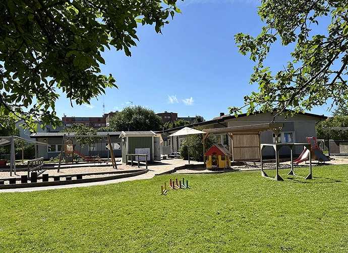 gräsmatta och gård med förskola i bakgrunden