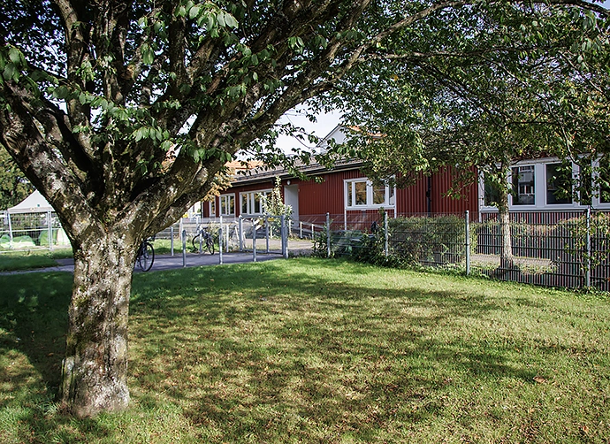 träd och staket och förskolan i bakgrunden
