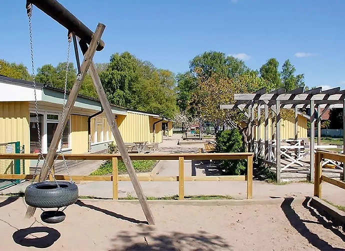 sandlåda med gungor framför förskolan