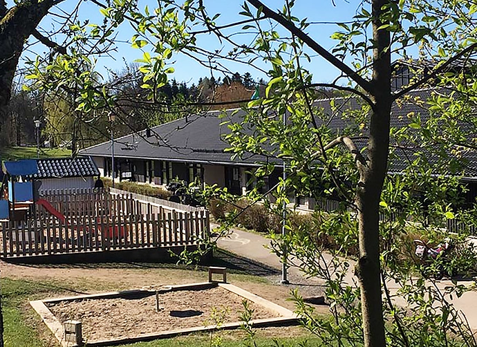 förskolegård med med träd och gräsmatta framför förskolan