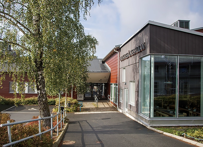 entré skolbyggnad med parkering och träd i förgrunden
