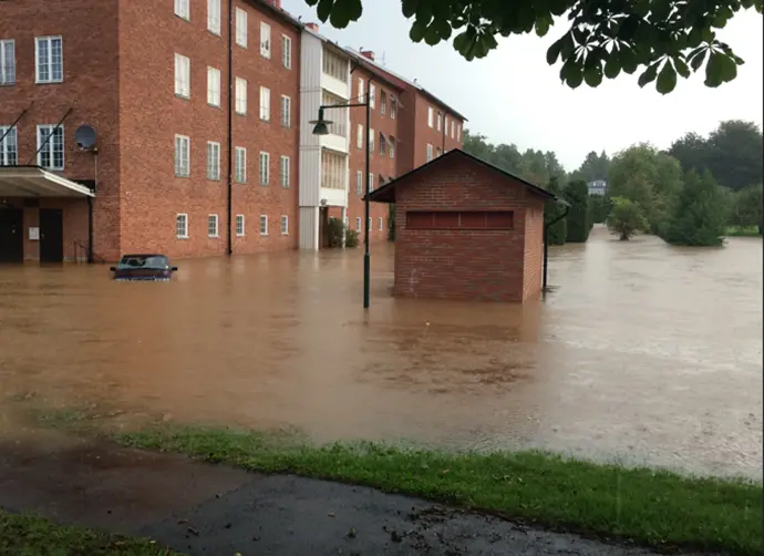 En gård framför ett flerbostadshus är översvämmat av dagvatten.