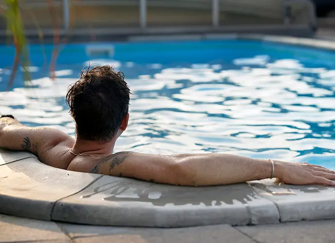 En person sitter i en pool i en trädgård.