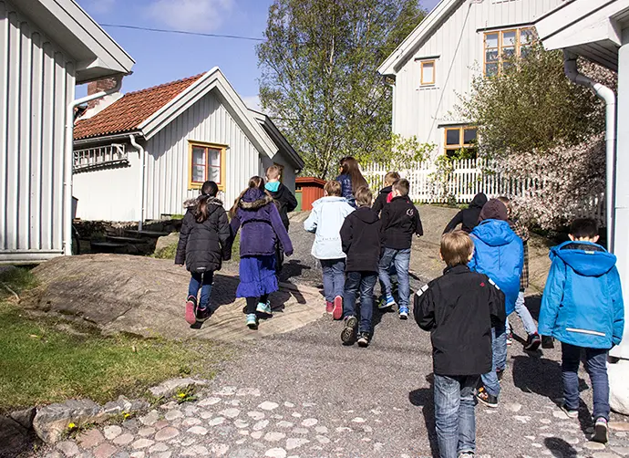En grupp barn går bland gamla trähus. 