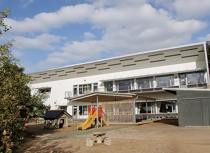 förskolegård med sandlåda och lekredskap med förskolan i bakgrunden