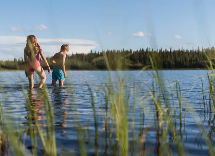 Två personer badar i en sjö.
