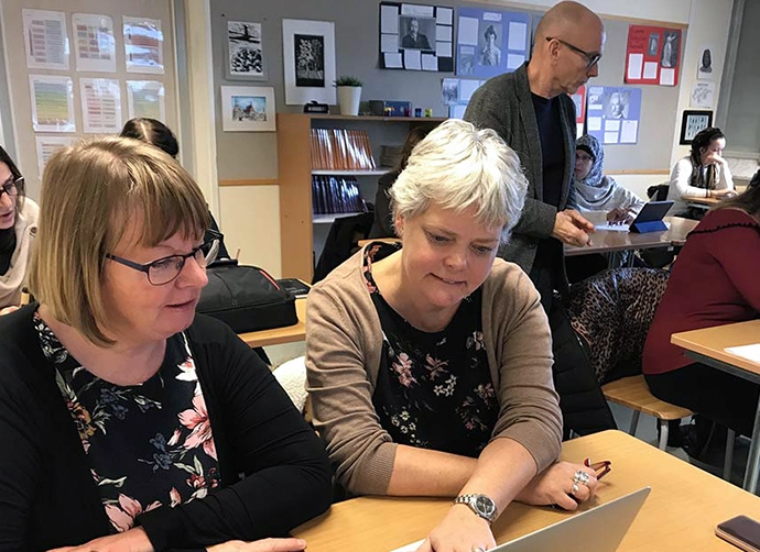 pedagoger sitter i ett klassrum och arbetar i par framför datorer