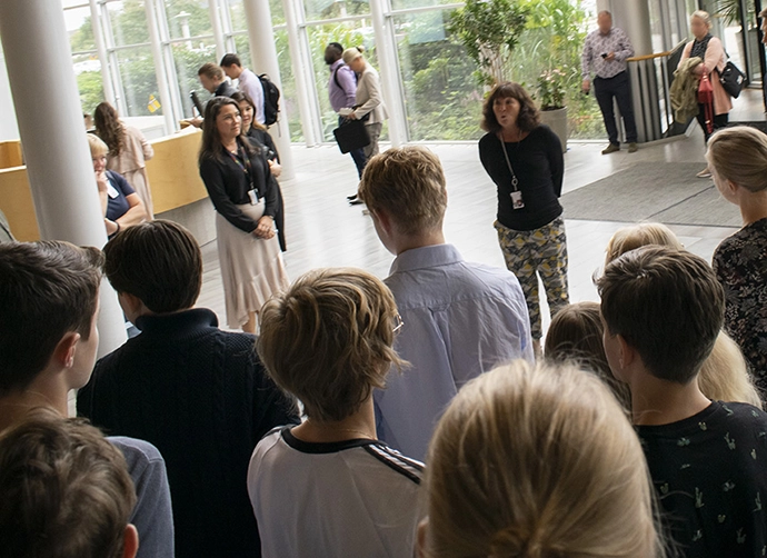 Personal på AstraZeneca står framför ett grupp elever på studiebesök