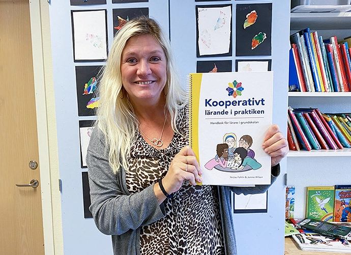 lärare i klassrummet håller upp en bok