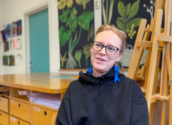 lärare sitter i sin bildsal med staffli i bakgrunden