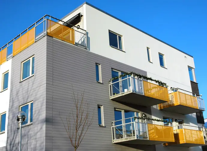 Flerfamiljshus i grått och vitt med gula inslag i balkongerna.