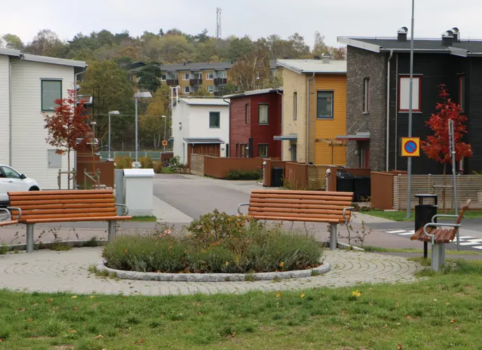 Olika typer av hus i bostadsområdet Kvarnbyvallen. En sittplats med träbänkar finns i området.