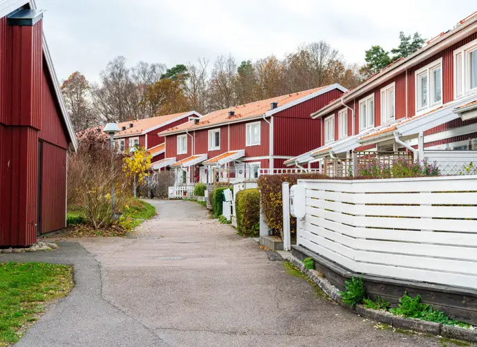 En väg kantad av röda radhus med vita staket i bostadsområdet Heljered i Kållered.