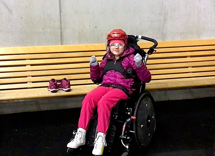 Elev sitter i en rullstol med skridskor på fötterna.