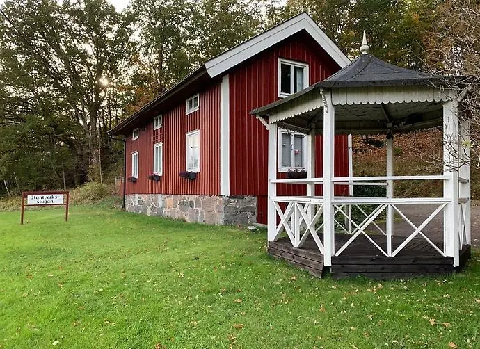 Hantverksstugan - ett rött hus med vita knutar och ett litet vitt lusthus