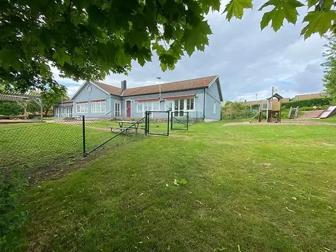 Gothenburg International School (GIS). En blå skolbyggnad i trä med en grön gräsmatta framför.