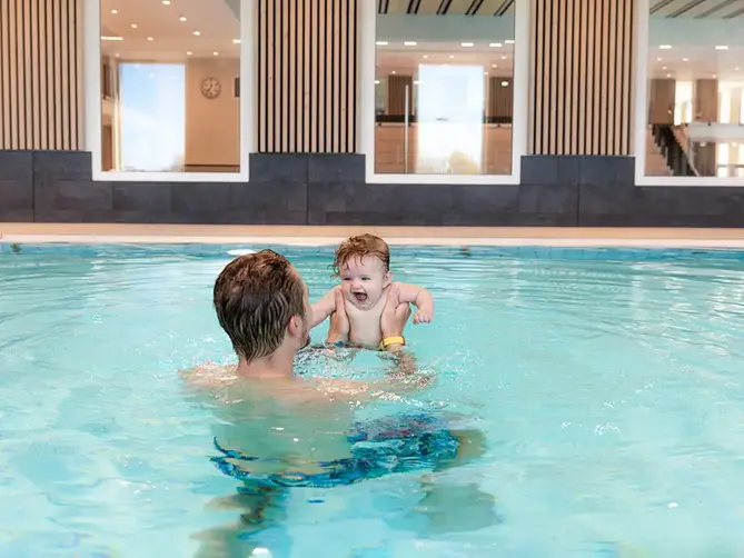 Pappa med bebis i varmvattenbassäng.