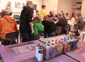 sprayburkar med färg i förgrunden och elever i bakgrunden