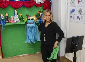 pedagog står med handdocka framför greenscreenskärm på förskolan