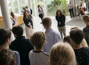 Personal på AstraZeneca står framför ett grupp elever på studiebesök