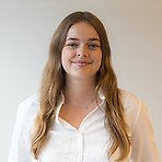 Emma har långt ljust hår, vit skjorta och ler mot kameran.