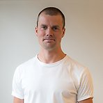 Filip har kort mörkt hår, vit t-shirt och ler lätt mot kameran.