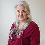 Josefin har långt ljust hår, vinröd tröja och ler mot kameran.