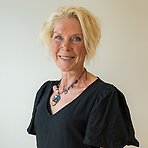 Sara har blont kort hår, svart blus och färgglatt halsband och ler mot kameran.