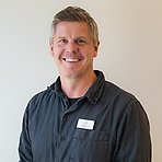 Niklas har kort ljust hår, mörk skjorta och ler mot kameran.