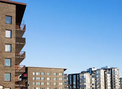 Bostadshus i Stallbacken. Tegelbeklädda bostadsbyggnader med balkonger och fönster mot en blå himmel.