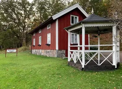 Hantverksstugan - ett rött hus med vita knutar och ett litet vitt lusthus